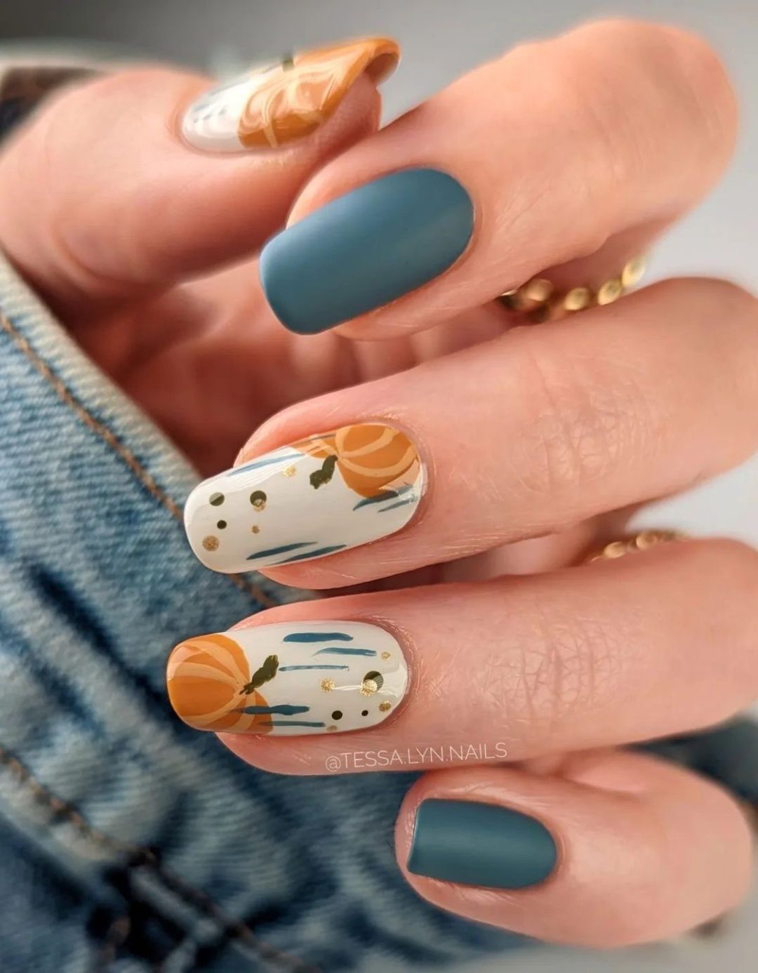 Matte teal nails with pumpkins.