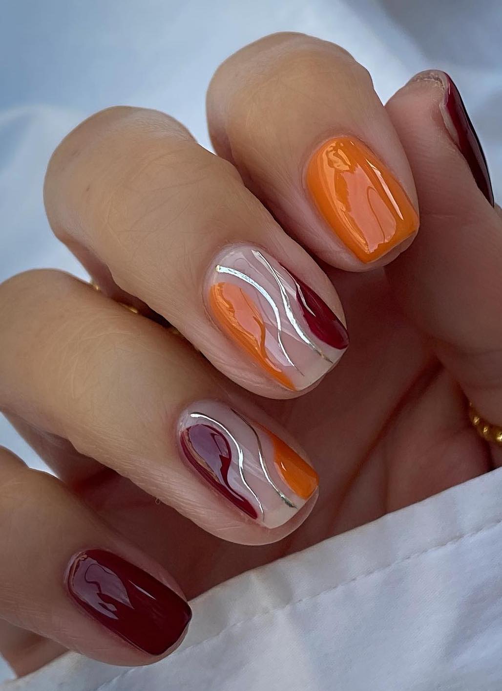 Burgundy and burnt orange swirl nails.