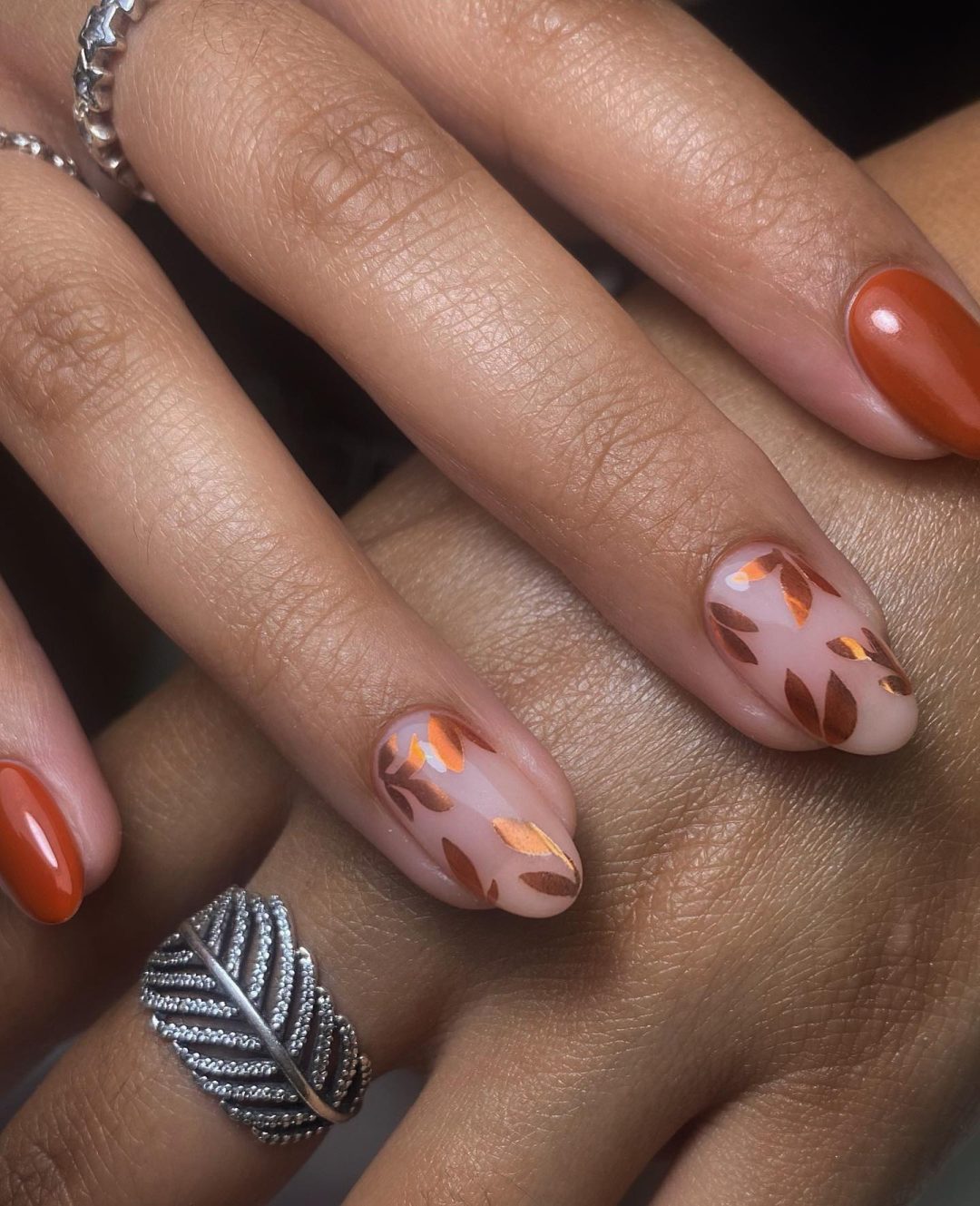 Burnt orange nails with leaf motif.