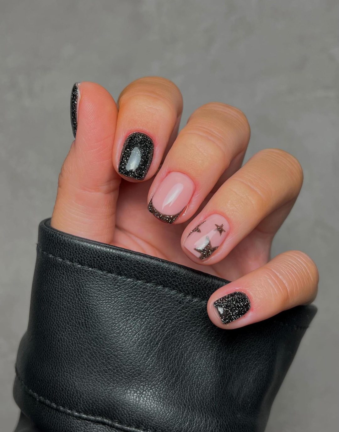 Short black glitter nails with stars.