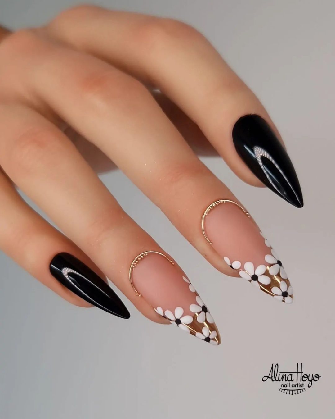 Black nails with gold French tips and white daisies.