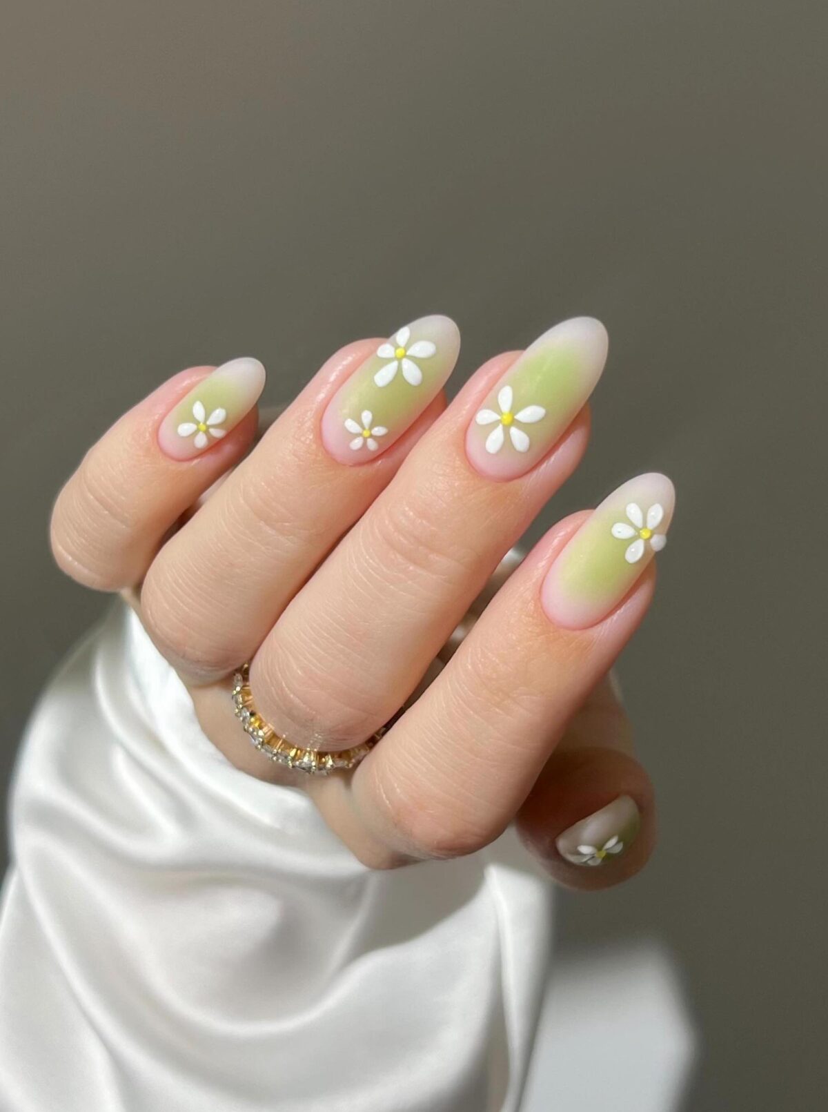 Lindas uñas de aura verde claro con un diseño de margaritas.