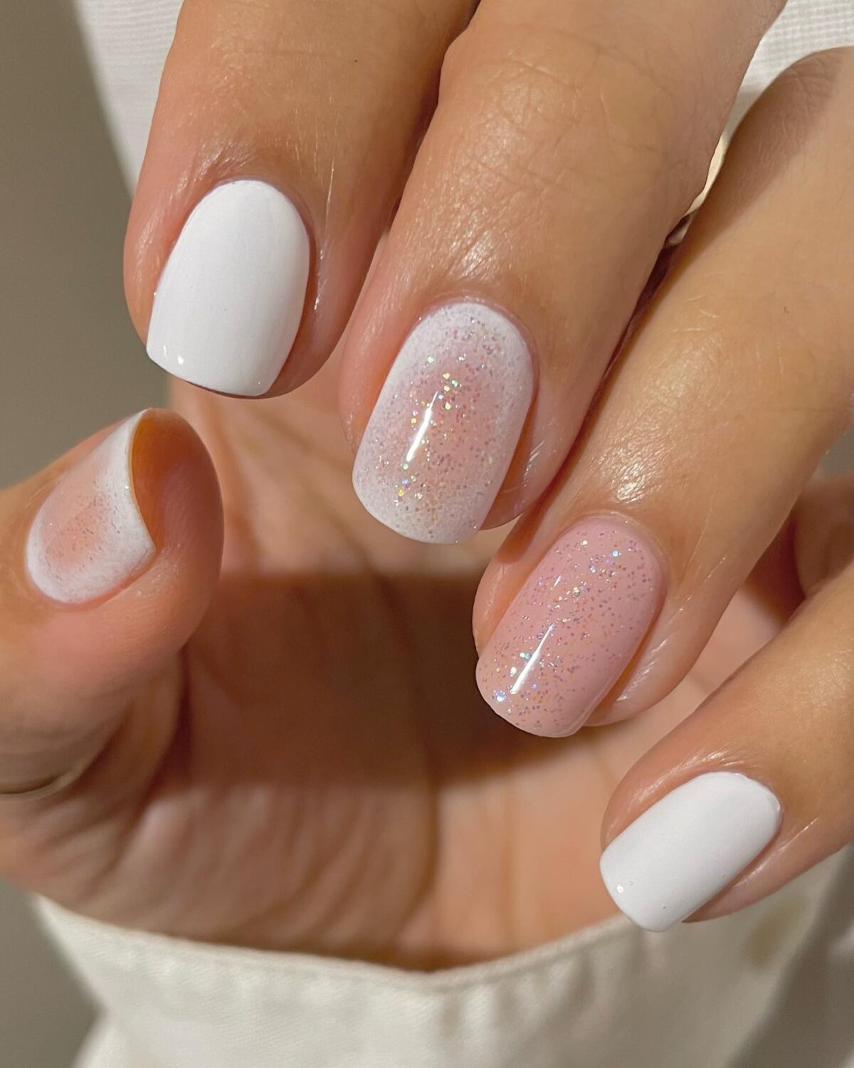 Uñas cortas de aura blanca y rosa con purpurina