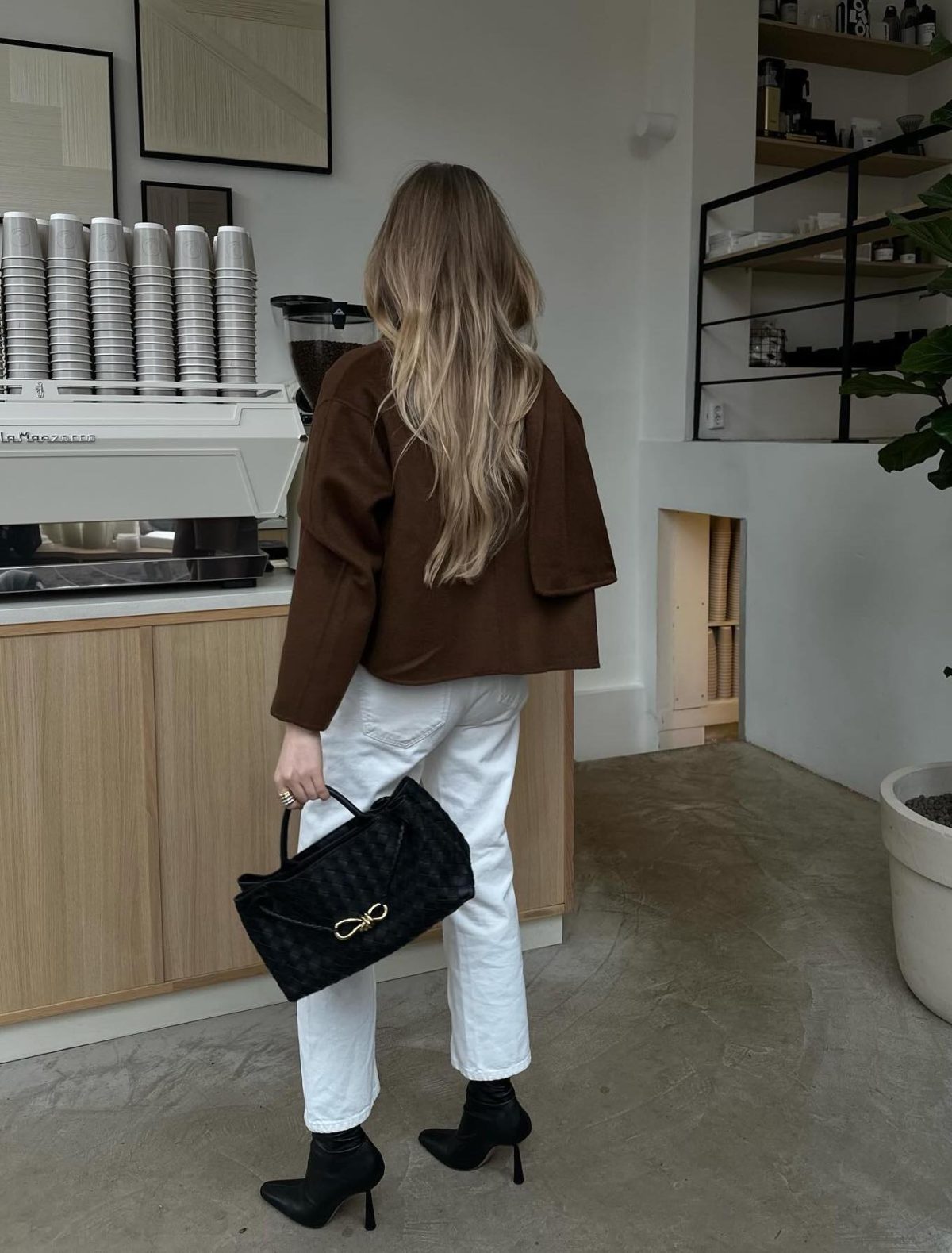 Casual outfit with white jeans, black sock boots, brown jacket and black Bottega Veneta East-West Andiamo bag.