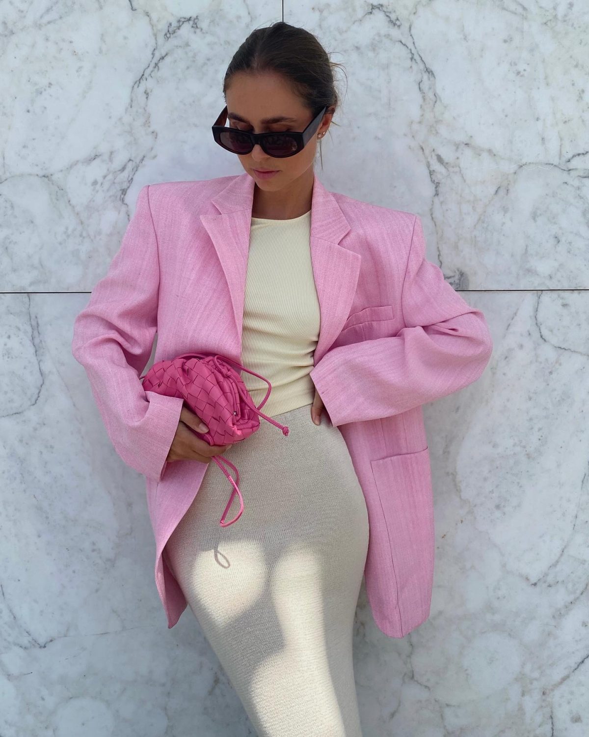 Cute spring outfit with a pink blazer, beige midi skirt and a hot pink Bottega Veneta small pouch bag.