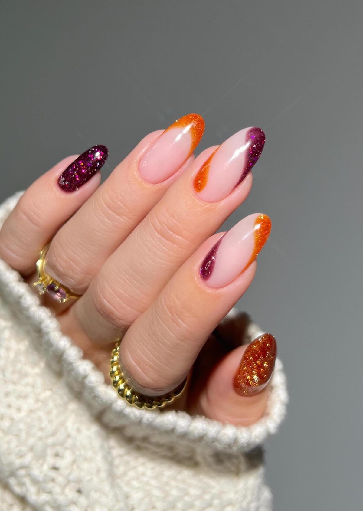 Uñas con efecto espiral en color naranja quemado y burdeos con brillo.