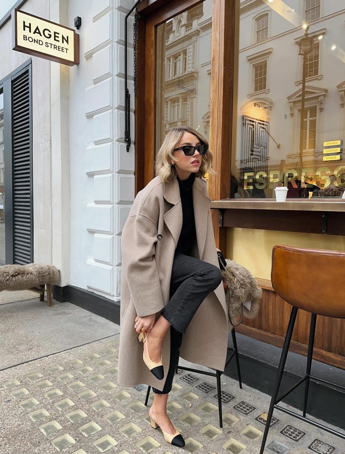 Casual spring outfit with a camel coat, black jeans and Chanel slingback heels.