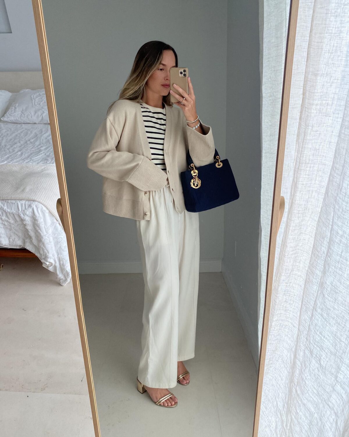 Chic casual outfit with white linen pants a beige cardigan and a navy Lady Dior bag